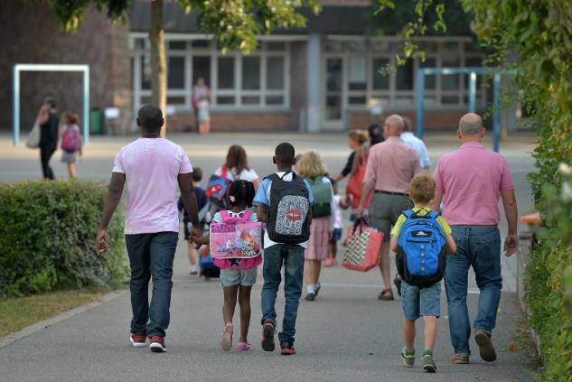 Des parents emmènent leurs enfants à l'école (©PATRICK HERTZOG - AFP)