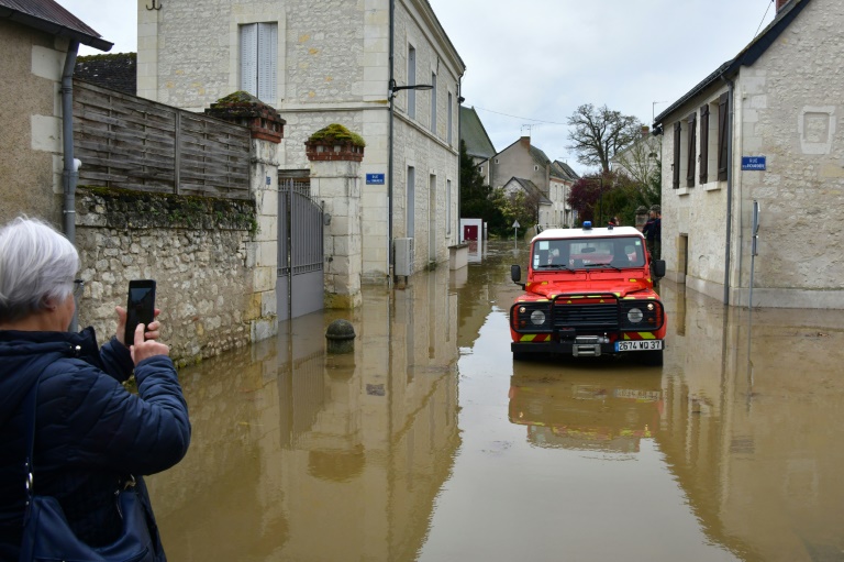 Une habitante prend en photo un véhicule des sapeurs-pompiers intervenant dans une rue inondée après des crues, le 31 mars 2024 à Nouâtre, en Indre-et-Loire