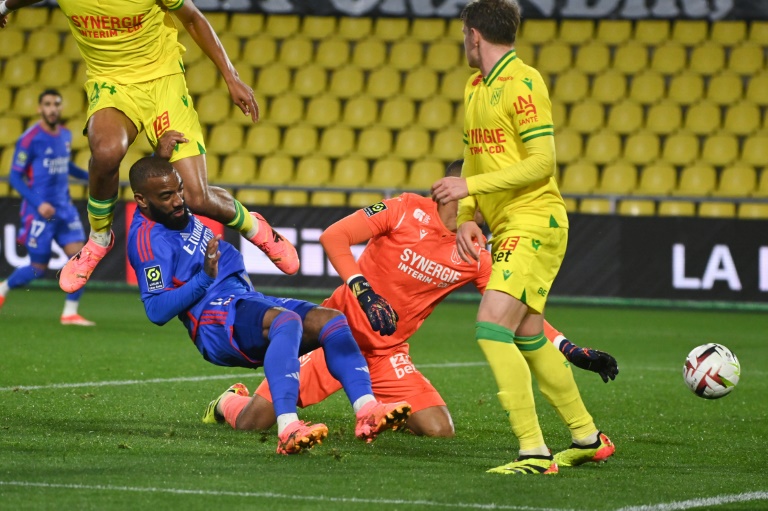 L'attaquant de Lyon Alexandre Lacazette (maillot bleu) réussit à tirer le ballon dans le but au milieu de trois joueurs nantais dont le gardien, au Stade de la Beaujoire à Nantes, le 7 avril 2024.