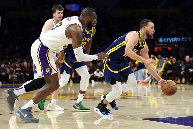Stephen Curry (D), des Golden State Warriors, poursuivi par LeBron James (G), des LA Lakers, lors d'un match de saison régulière de NBA, le 16 mars 2024 à Los Angeles