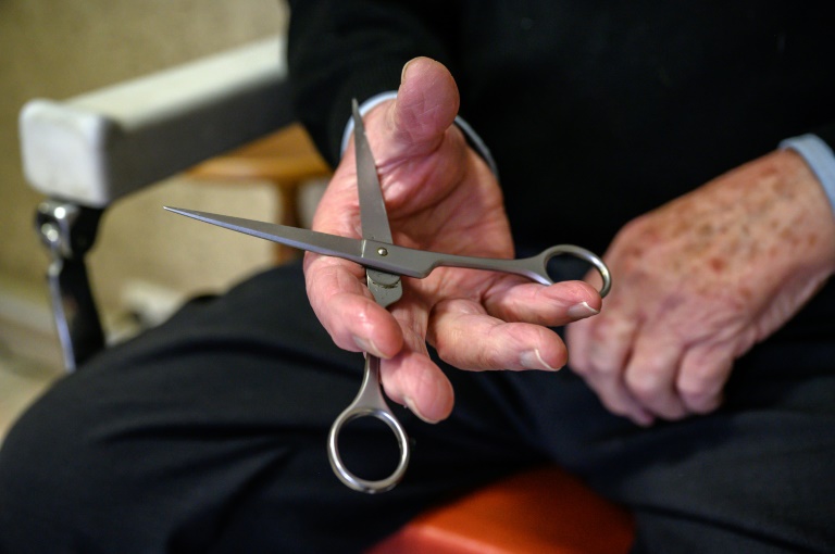 Le coiffeur Roger Amilhastre, âgé de 90 ans, tient une paire de ciseaux dans son salon à Saint-Girons, en Ariège, le 16 avril 2024