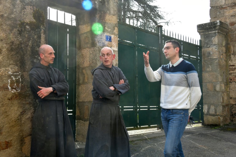 Le maire de Solignac, Alexandre Portheault (D), discute avec le père Benoît Joseph (C) et le père André à la porte de l'abbaye de Solignac, en Haute-Vienne, le 21 mars 2024