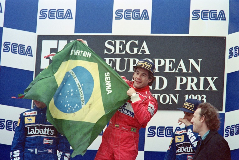 Ayrton Senna, alors pilote chez McLaren, brandit le drapeau brésilien sur le podium du Grand Prix d'Europe, le 11 avril 1993 à Donington (Royaume-Uni)