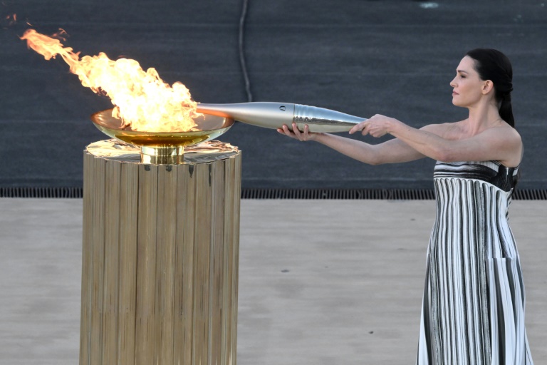 L'actrice grecque Mary Mina dans le rôle d'une grande prêtresse allume la flamme olympique lors de la cérémonie de remise aux orgnaisateurs des JO-2024 de Paris, le 26 avril 2024 à Athènes