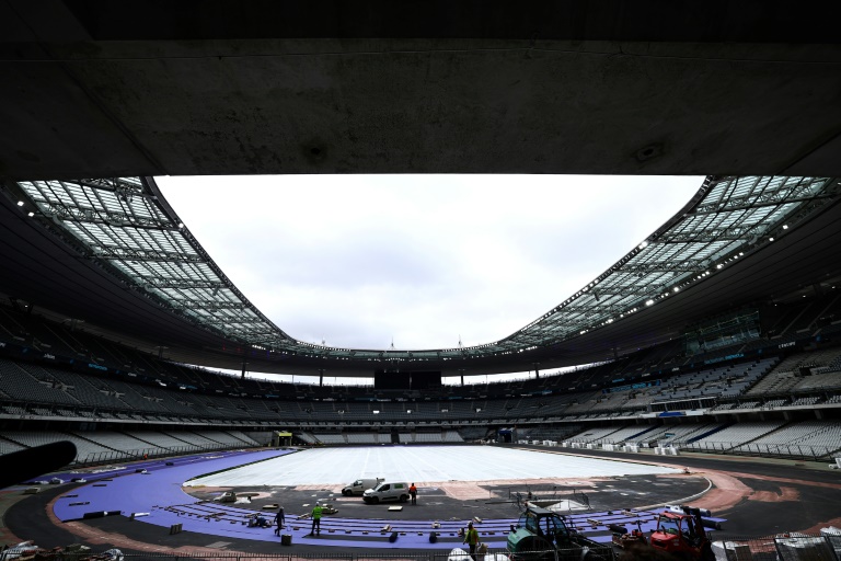 Des ouvriers posent des pistes d'athlétisme violettes pendant les travaux de rénovation pour adapter le Stade de France en vue des Jeux olympiques de Paris 2024, à Saint-Denis, en banlieue parisienne, le 9 avril 2024