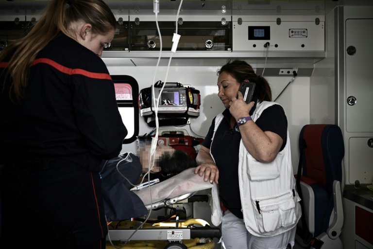 Pascale Martinet (d), infirmière anesthésiste et membre de l'une des premières unités hospitalières mobiles paramédicales (UMH-P) du CHU de Bordeaux, parle au téléphone dans un camion de pompiers utilisé pour transporter un patient suite à un appel d'urgence, le 17 avril 2024 à Bordeaux