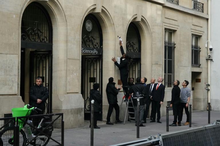 Un agent de sécurité retire une affiche à l'entrée de Sciences Po Paris, après que des étudiants ont pénétré à l'intérieur pour un rassemblement propalestinien, le 7 mai 2024 à Paris