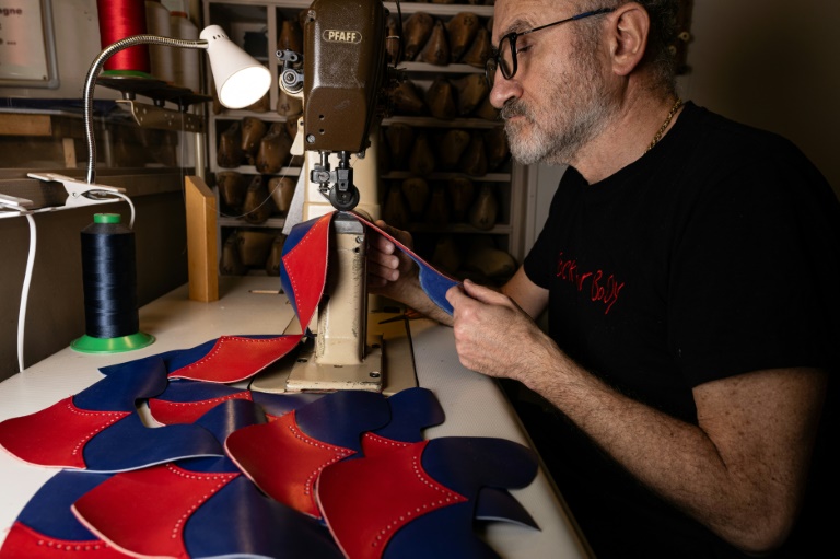 Un bottier prépare des pièces de cuir pour les bottes utilisées par les danseurs du cabaret musical du Moulin Rouge à l'atelier de la maison Clairvoy à Paris, le 12 mars 2024