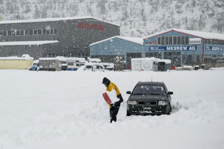 Un homme essaie de dégager sa voiture prise dans la neige, le 17 avril 2025 à Steg, dans le canton du Valais, en Suisse