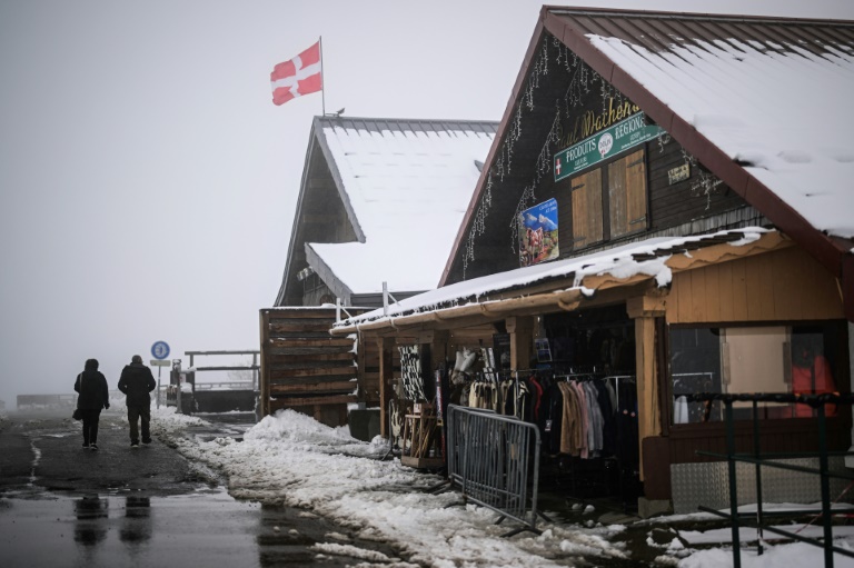 Des passants près de chalets après de fortes chutes de neige au col des Aravis, près de La Clusaz, en Haute-Savoie, le 17 avril 2025