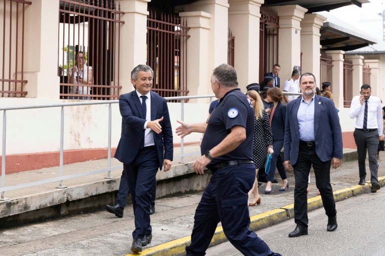 Le ministre de la Justice Gerald Darmanin (g) salue un officier de police dans les rues de Cayenne lors de sa visite en Guyane, le 19 mai 2025