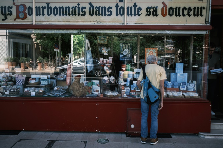 Un client regarde les boîtes de pastilles Vichy et les produits exposés dans la vitrine d'une boutique de la confiserie Maison Moinet à Vichy, le 13 mai 2025 dans l'Allier