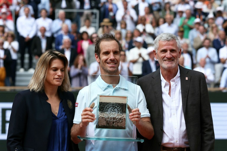Entouré d'Amélie Mauresmo, directrice du tournoi, et de Gilles Moretton, président de la FFT, Richard Gasquet reçoit un trophée récompensant l'ensemble de sa carrière.