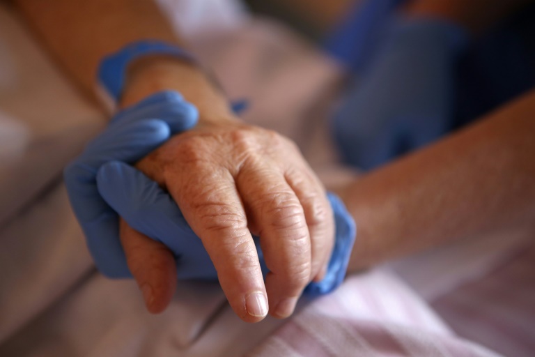 Un personnel soignant tient la main d'un patient en soins palliatifs, à l'hôpital Eugénie d'Ajaccio, le 23 avril 2020