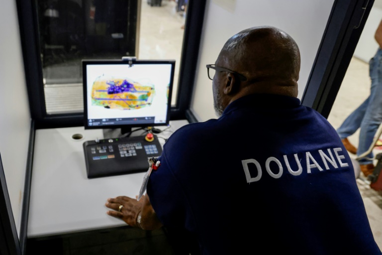 Un douanier français scanne le bagage d'un passager se rendant à Paris à l'aéroport international Félix-Eboué de Cayenne, le 24 mars 2024