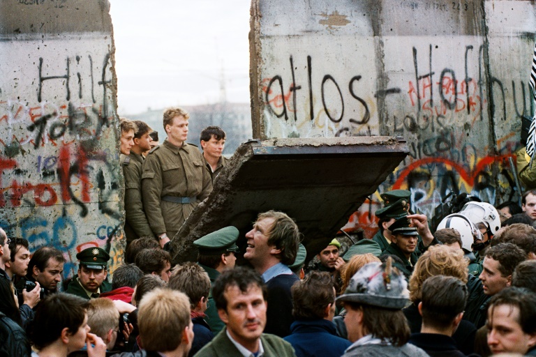 Des Berlinois de l'Ouest devant le mur de Berlin, tôt le 11 novembre 1989, alors que des gardes-frontières est-allemands démolissent une section du mur pour ouvrir un nouveau point de passage entre Berlin-Est et Berlin-Ouest, près de la place Potsdamer