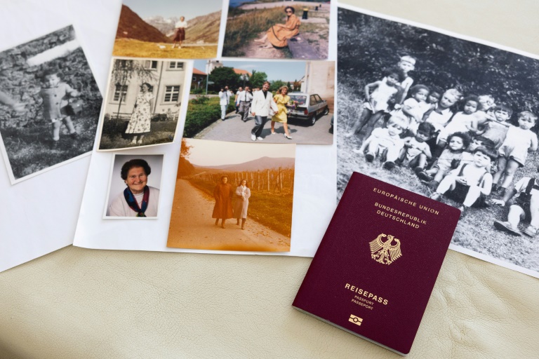 Une photo de Claudine Spire enfant (g), son passeport allemand et des photos de ses proches en Allemagne, lors d'un entretien à son domicile de Chaville, dans la région parisienne, le 9 avril 2025