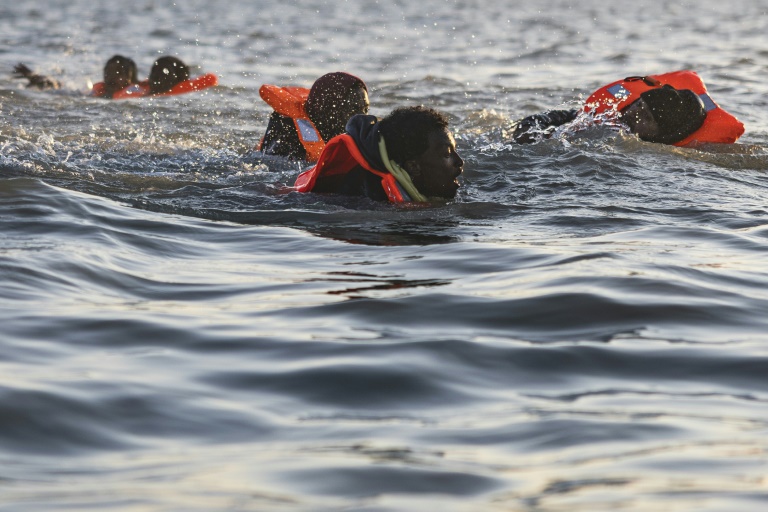 Des migrants nagent alors qu'ils tentent de monter à bord d'un bateau de passeurs pour traverser la Manche au large de la plage de Gravelines, le 16 juin 2025 dans le Nord