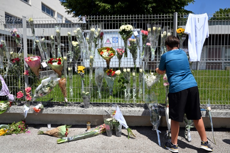 Un élève accroche des fleurs sur les grilles du collège Françoise-Dolto à Nogent, en Haute-Marne, au lendemain du meurtre d'une surveillante, le 11 juin 2025