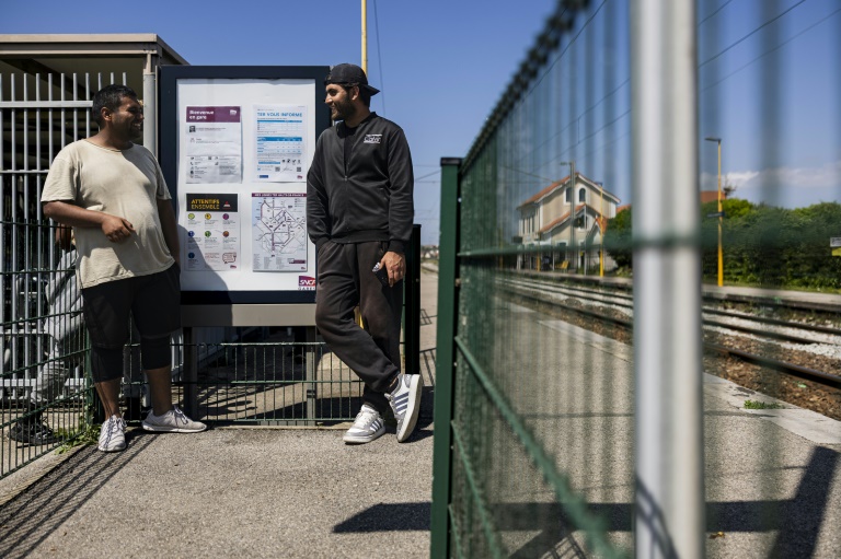 Des Afghans en quête d'ombre à la gare de Wimille-Wimereux le 18 juin 2025, non loin des baigneurs venus nager et bronzer sur la côte d'Opale