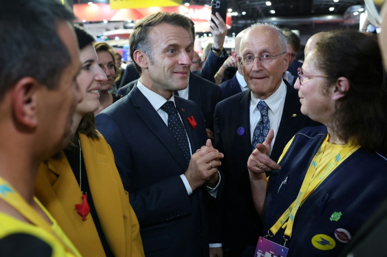 Le président français Emmanuel Macron se tient aux côtés du PDG du groupe La Poste, Philippe Wahl, et d'employés de La Poste au salon VivaTech, à Paris, le 11 juin 2025
