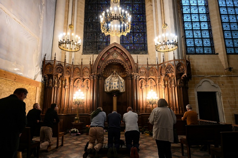 Des personnes prient à la chapelle Notre-Dame du Pilier et sa statue en noyer polychrome de la Vierge Marie perchée sur un pilier doré dans la cathédrale Notre-Dame de Chartres, le 5 juin 2025 en Eure-et-Loire