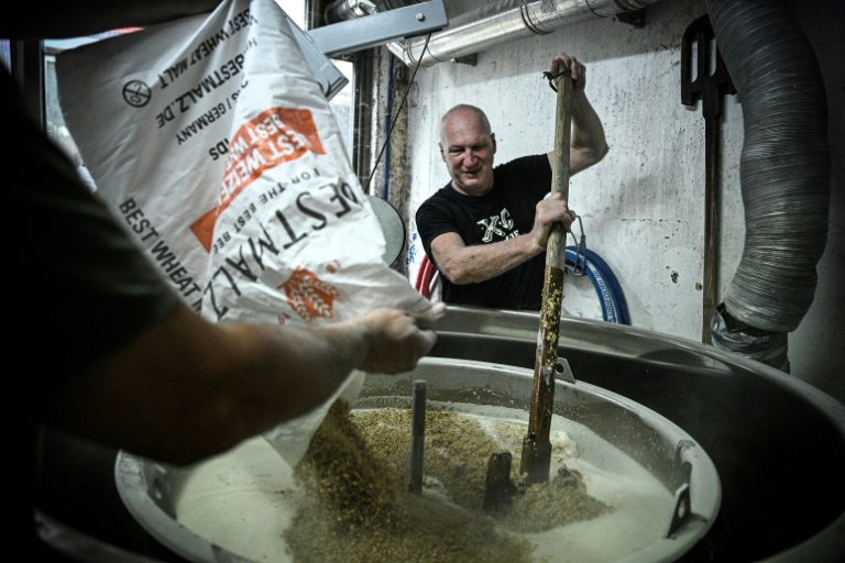 Un employé verse du malt dans une cuve lors d'une opération de brassage, le 20 juin 2025 dans la Brasserie Croix de Chavaux à Montreuil, en Seine-Saint-Denis
