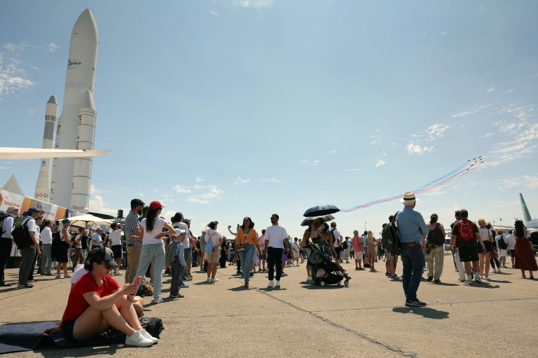 Des visiteurs regardent des avions de la patrouille de France pendant la 55e édition du Salon international de l'aéronautique et de l'espace à l'aéroport du Bourget, au nord de Paris, le 20 juin 2025