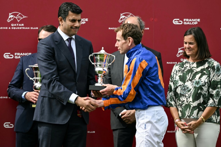 Le jockey britannique Ryan Moore (c) reçoit le trophée du 185e Prix du Jockey-Club, le 1er juin 2025 à Chantilly, dans l'Oise