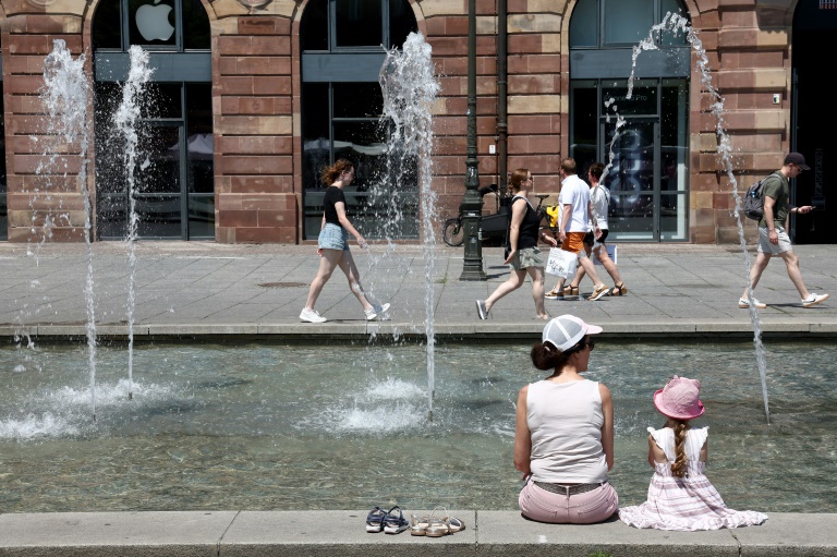 Des habitants et des touristes se rafraîchissent près de la fontaine de la place Kléber à Strasbourg, dans l'est de la France, le 19 juin 2025