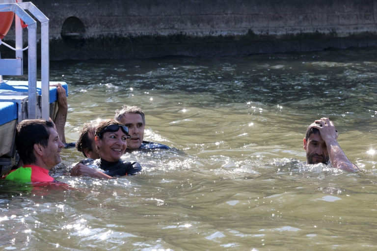 La maire de Paris Anne Hidalgo (g) et Tony Estanguet (d), membre du Comité d'organisation des Jeux paralympiques (Cojo), nagent dans la Seine, à Paris, le 17 juillet 2024, pour démontrer que le fleuve est suffisamment propre pour accueillir les épreuves de natation en plein air des Jeux olympiques de Paris