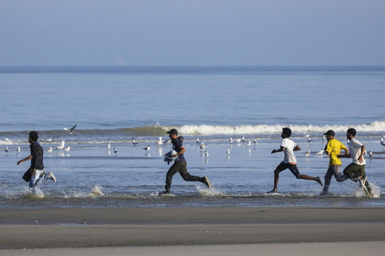 Des migrants courent sur la plage d'Equihen (Pas-de-Calais), le 30 juin 2025, pour tenter d'embarquer à destination de l'Angleterre