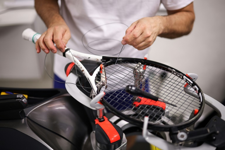 Une raquette du N.1 mondial Jannik Sinner entre les mains d'un cordeaur à l'atelier de cordage de Wimbledon le 5 juillet 2025 à Londres