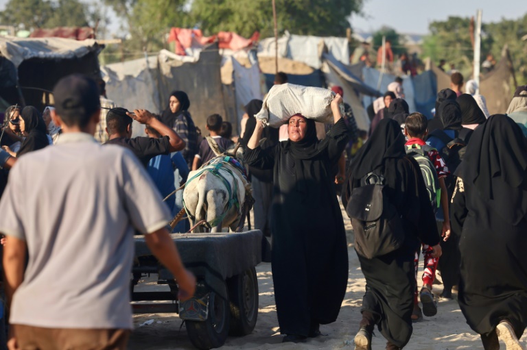 Une Palestinienne porte un sac d'aide humanitaire reçu à un point de distribution à Rafah, le 24 juillet 2025 dans le sud de la bande de Gaza