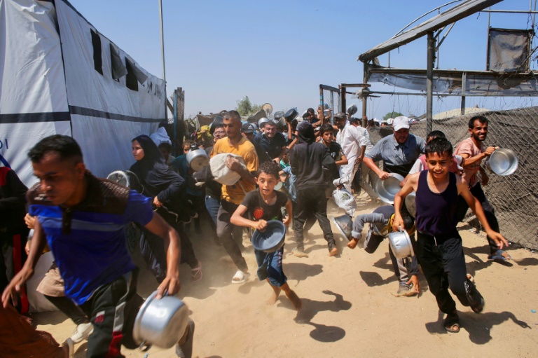 Des Palestiniens courent pour faire la queue à une cuisine caritative à Khan Yunis, dans le sud de la bande de Gaza, le 22 juillet 2025