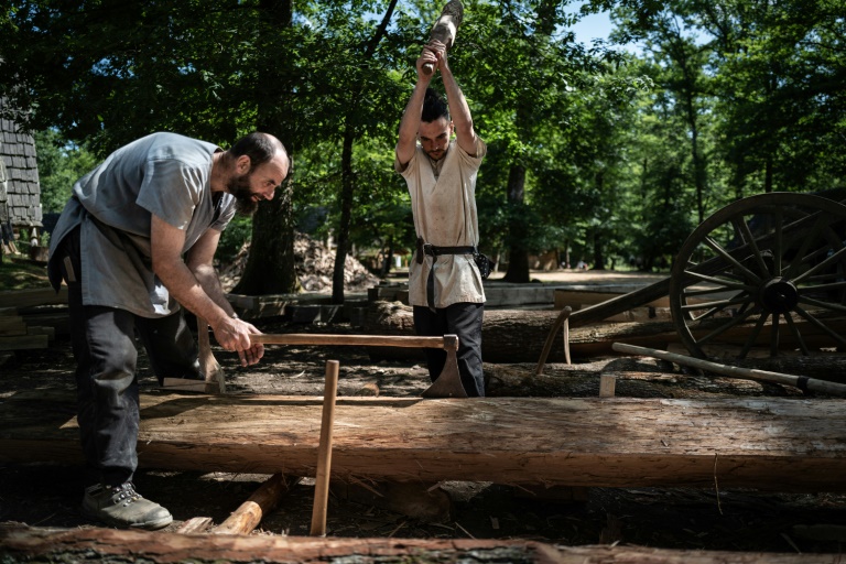 Des charpentiers fendent un tronc d'arbre sur le chantier de construction du château de Guédelon à Treigny, le 23 juin 2025 dans l'Yonne
