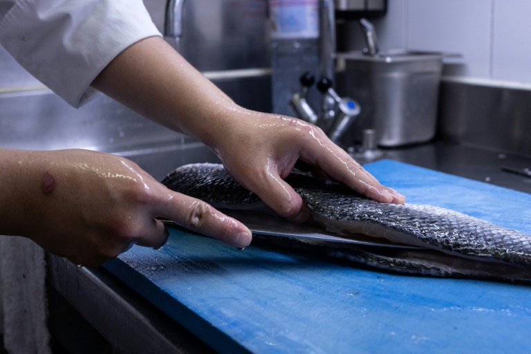 Un cuisinier prépare un bar dans la cuisine du restaurant L'Ambroisie du chef Bernard Pacaud, le 3 juillet 2025 à Paris