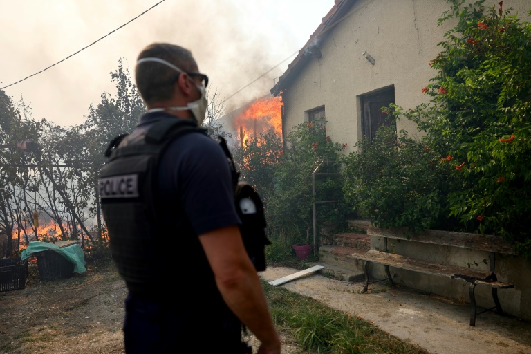 Un policier près d'un incendie de forêt se propageant dans le quartier de l'Estaque à Marseille, le 8 juillet 2025 dans les Bouches-du-Rhône