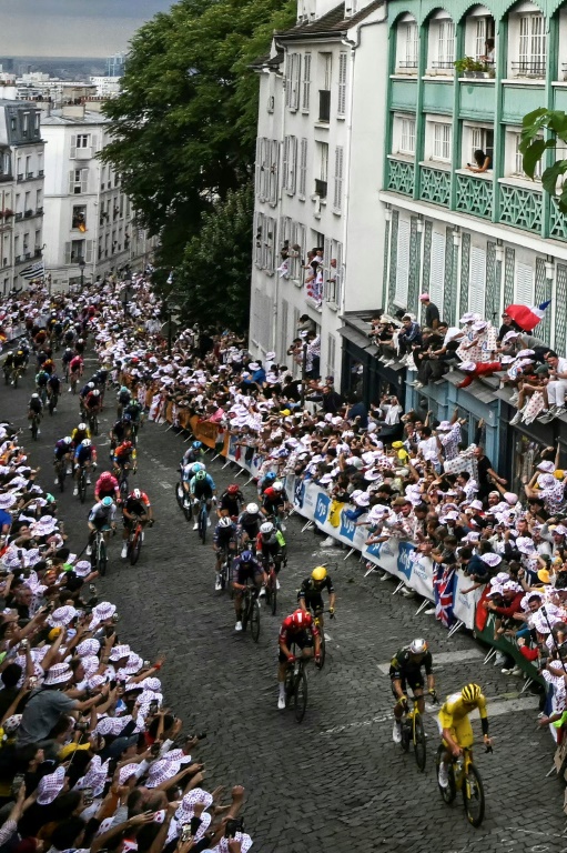 Le maillot jaune Tadej Pogacar roule avec le peloton dans la montée de la rue Lepic sur la Butte Montmartre, en passant devant le moulin de la Galette, lors de la 21e et dernière étape du Tour de France le 27 juillet 2025