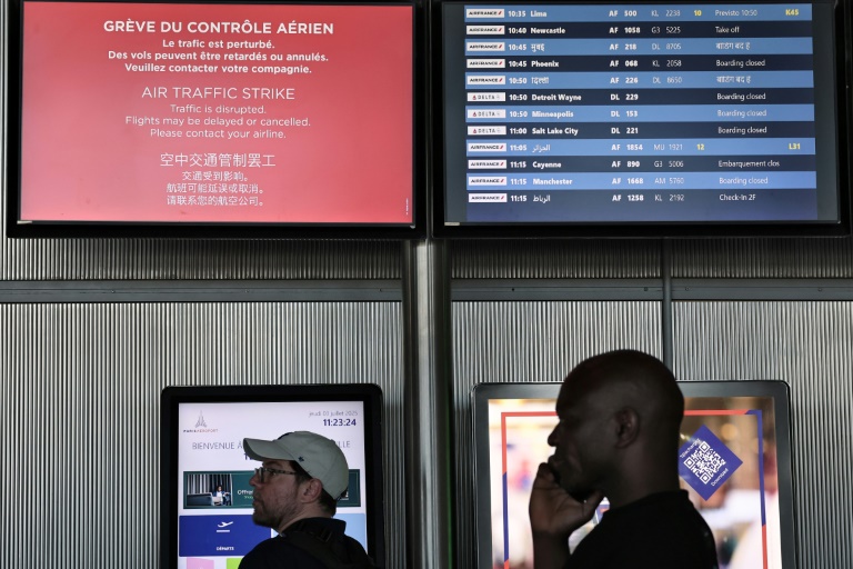 Des passagers consultent le tableau d'affichage des départs à l'aéroport Roissy Charles-de-Gaulle, près de Paris, pendant la grève des contrôleurs aériens français, le 3 juillet 2025