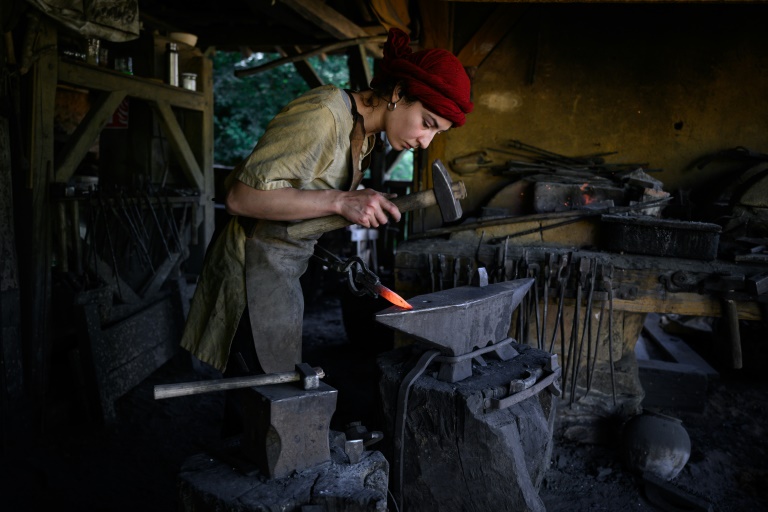 Une forgerone fabrique des outils en fer sur le chantier de construction du château de Guédelon, un château médiéval construit uniquement selon les méthodes du XIIIe siècle, à Treigny, le 23 juin 2025 dans l'Yonne