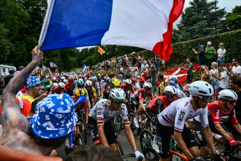 Des spectateurs, dont un brandit un drapeau français, encouragent les coureurs du Tour de France, lors de la première étape disputée dans le Nord, le 5 juillet 2025