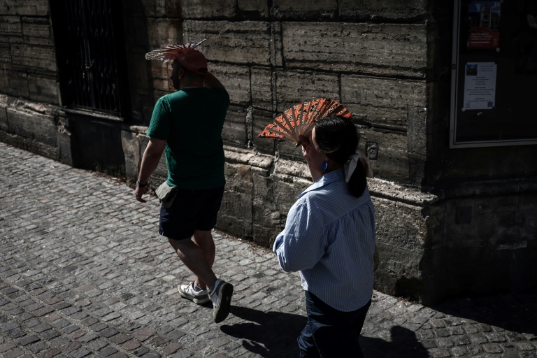 Passers -by protect themselves from the sun on last day heat wave france July 1, 2025 in Paris during a heat wave