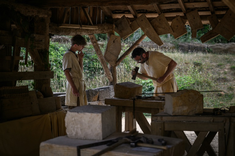 Des tailleurs de pierre travaillent sur le chantier de construction du château de Guédelon, un château médiéval construit uniquement selon les méthodes du XIIIe siècle, à Treigny, le 23 juin 2025 dans l'Yonne