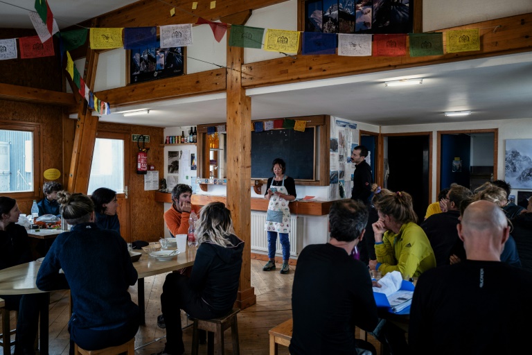 La gardienbe du refuge de la Selle annonce la météo des prochains jours aux alpinistes à la fin du dîner dans le massif des Écrins, à Saint-Christophe-en-Oisans, le 8 juillet 2025