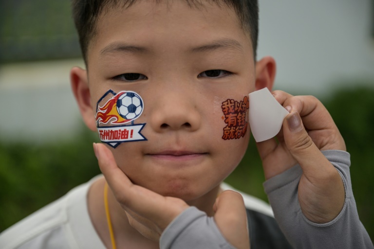 Un enfant porte les couleurs de son club du championnat amateur en allant voir le match entre Suzhou et Yangzhou, le 29 juin 2025 à Kunshan