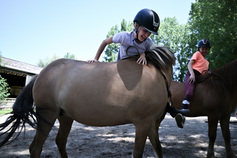 Un enfant tente de monter sur un poney dans la ferme équestre de Bois Guilbert, en Seine-Maritime, le 1er juillet 2025