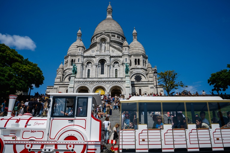 Un petit train passe devant la basilique du Sacré-Coeur, le 5 août 2025 à Paris