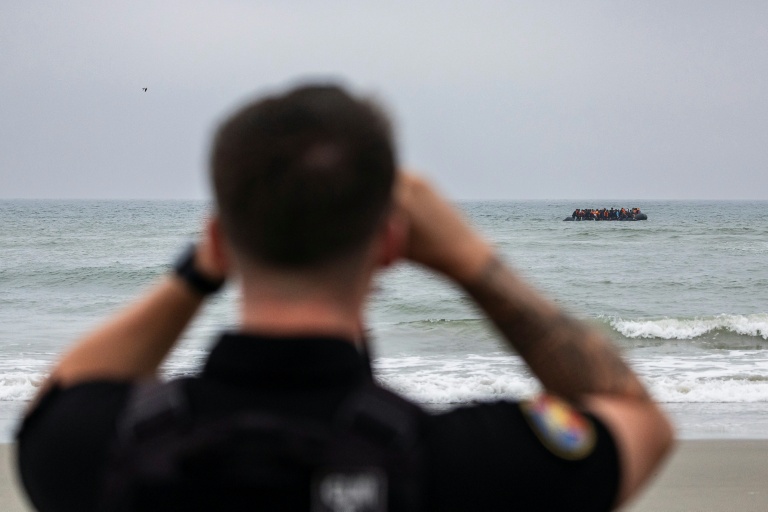 Un gendarme observe des migrants qui tentent la traversée de la Manche à Neufchatel-Hardelot, le 13 août 2025