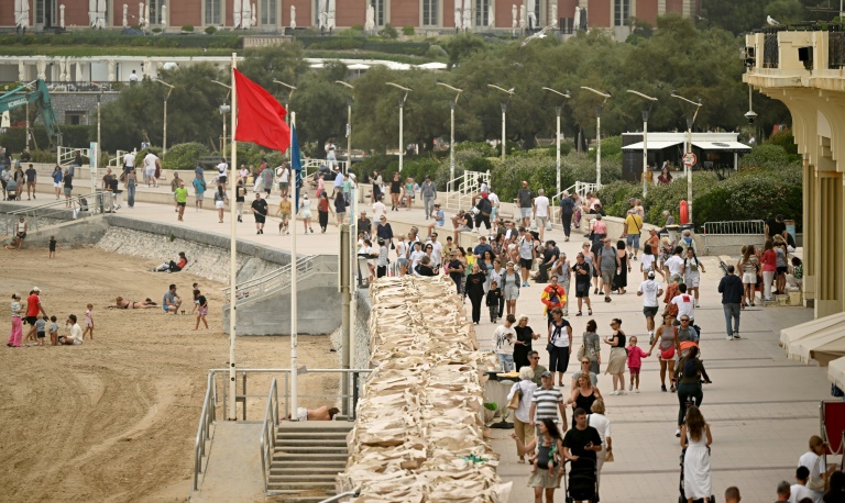 Un drapeau rouge interdisant la baignade sur la Grande plage de Biarritz, le long de laquelle marchent de nombreux promeneurs le 26 août 2025